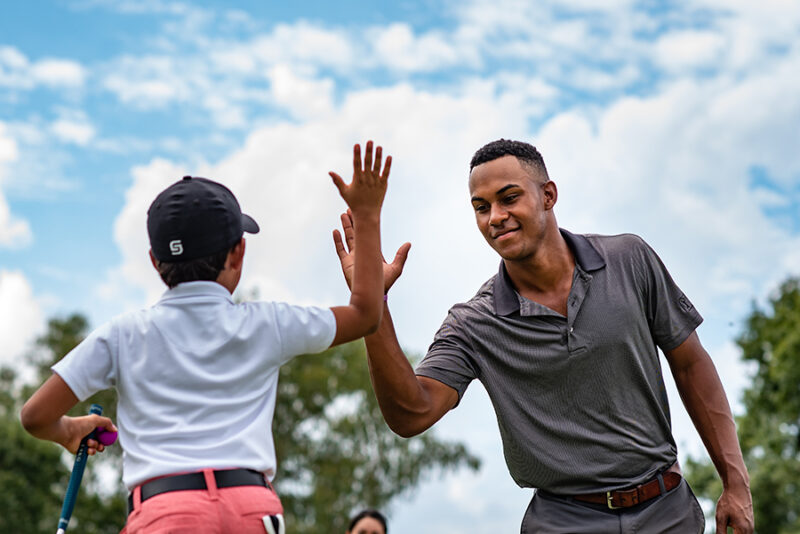 First Tee coach and participant high-five.