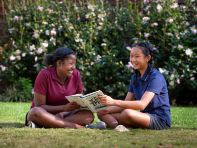 Two girls reading a book about golf.