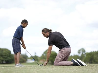 Coach helping a participant on the driving range.