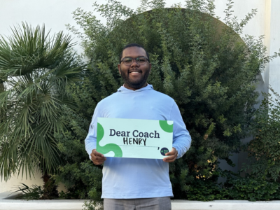 Alumni holding Dear Coach sign