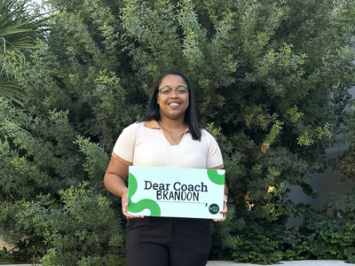 Alumni holding Dear Coach sign